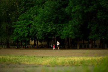 Athletic young father and little daughter running in stadium at sunset. Healthy lifestyle