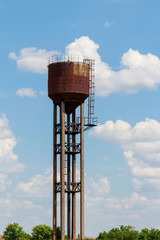 Old rusty water tower in the green field