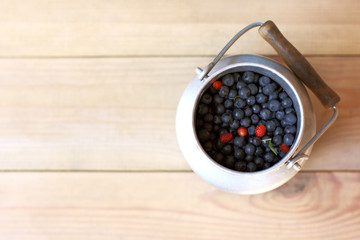 Fototapeta na wymiar freshly picked forest berries/ blueberries in a metal container on a wooden table top view