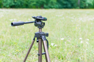 A tripod for the camera standing on a green glade. © Konstiantyn Zap