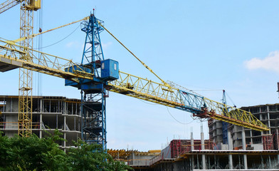Fototapeta na wymiar Crane near buildings. Construction site. Concrete building under construction.