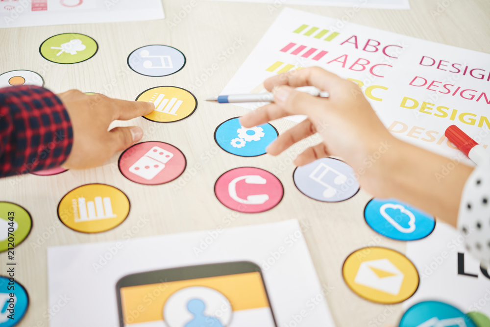 Wall mural crop shot of coworking man and woman choosing colorful icon for mobile application while creating ne
