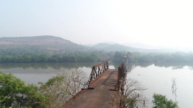Aerial view. The rusty remains of the trusses of the bridge on opposite banks of the muddy river. 