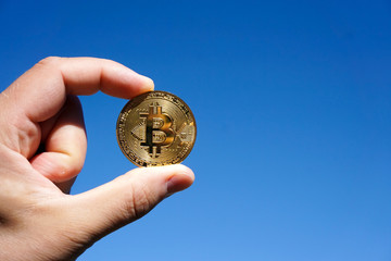 Fototapeta na wymiar Hand hält Bitcoin Münze in den Himmel