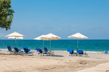 Obraz na płótnie Canvas chairs and umbrellas on beach with tree