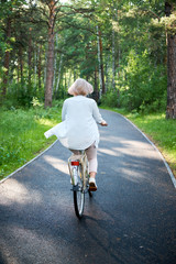 Fototapeta premium Young beautiful woman riding a bicycle in a park. Active people. Outdoors relax