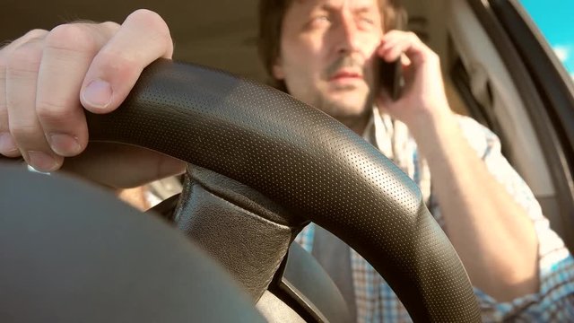 Man driving car and talking on mobile phone, dangerous and reckless behavior in traffic