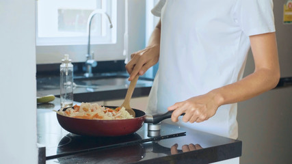 Woman mixing ingredients vegetables on the frying pan, close-up