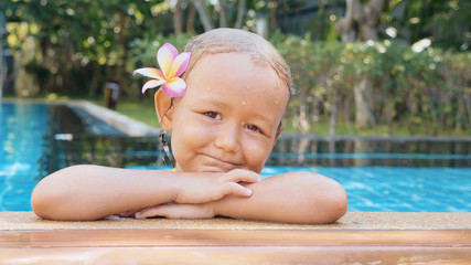 Portrait of happy child girl smiling on the edge of swimming pool