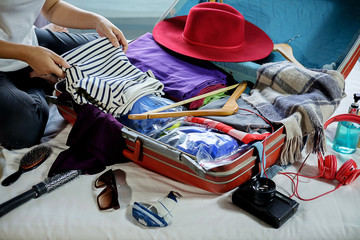Fototapeta na wymiar People packed suitcase with travel accessories on bed. Vacation concept