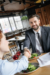 Businesspeople having business lunch at restaurant sitting eating salad drinking wine agreement