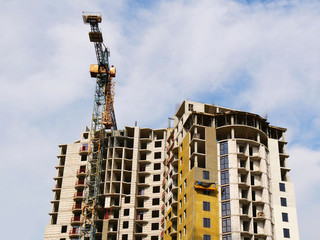 Crane near building under construction. Construction site against blue sky.