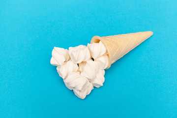 Fototapeta na wymiar flat lay. sweet marshmallow horn in the form of an ice cream in a waffle cup on a blue background