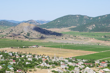 Russia, the Republic of Crimea, Sudak city district, Vesyoloe village. 06/08/2018: View of a settlement in a mountain valley: houses, outbuildings, vineyards