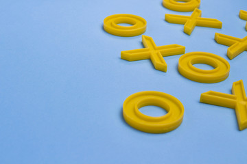 Yellow plastic crosses and zeroches for playing tic-tac-toe on a blue background. Concept XO Win...