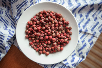 Red field strawberries on white plate on wooden table