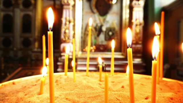 Video of burning candles. In the background, the icon with the Holy face.