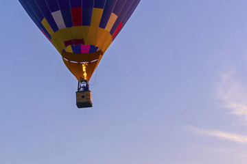 Fototapeta premium the bottom of a flying balloon (aerostat), with aeronauts in a basket and a burning fire, against a blue sky