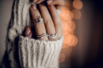 Hands with beautiful silver rings on golden bokeh lights background