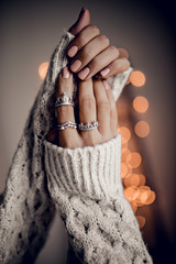 Hands with silver rings on golden bokeh lights background - obrazy, fototapety, plakaty