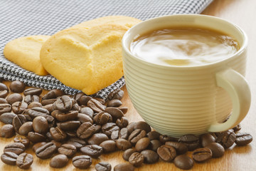 Cup Of Coffee With Cookies And Roasted Coffee Beans On Table In Morning.