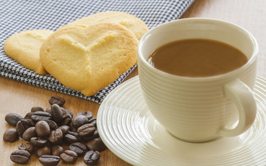 Cup Of Coffee With Cookies And Roasted Coffee Beans On Table In Morning.