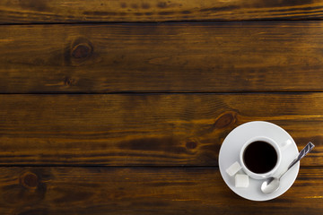 Black coffee with 2 sugars, white cup on a brown wooden table. Top view