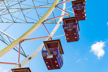 Ferris wheel against the blue sky. Empty red cabins close up