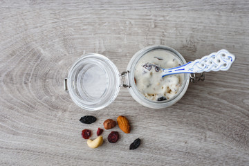 Homemade ice cream in a glass jar, nuts, raisins and a decorative spoon on a wooden background