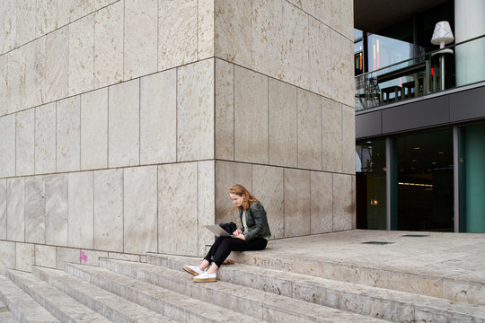 Amsterdam, june 2018. A 21 year old student sits on the stairs of the public library of Amsterdam, working on het laptop.
