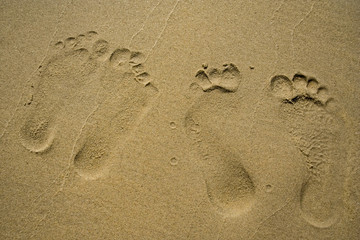 Close-up of footprints from a couple on powdery fine sand at Pantai Cenang, a beach on Langkawi Island, Malaysia.