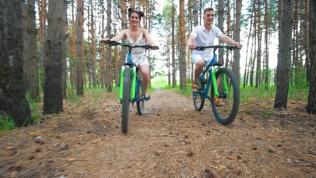 Caucasian young couple having fun enjoying cycling in forest