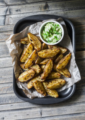 Roasted spices potato with avocado salsa on wooden background, top view. Delicious snack or appetizers. Vegetarian food