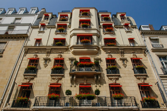 Paris residential building with red awnings. Old Paris architecture, beautiful facades, typical french houses. Famous travel destinations in Europe. City life, lifestyle, expensive real estate concept