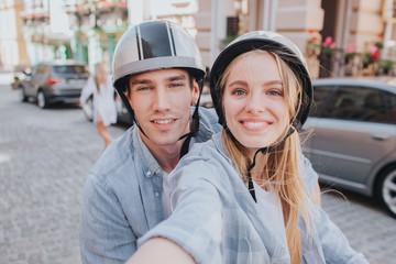 Beautiful couple is sitting on motorcycle's seats and looking on camera. Girl is holding camera....