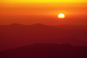 Beautiful golden sunrise. Red sky with sun and mountain range, natural outdoor travel background