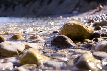 sunset at the beach. water covering the rocks on the shore. People on the background. Summer, holidays. Ibiza