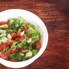 Salad in a plate on a wooden background. Food