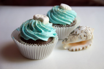Two cupcakes with goby cream and a seashell.