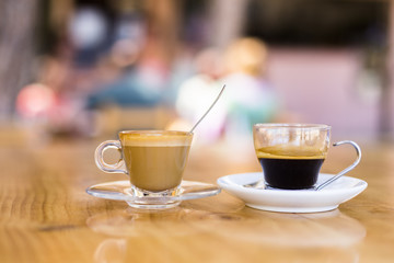 Fototapeta premium two cups of coffee on a wood table in a terrace. Summertime, people on the background. Holidays and lifestyle