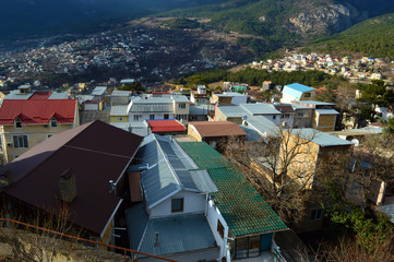The roofs of small houses are played in different colors. The buildings are located in a cozy gorge. 