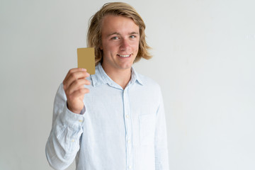 Portrait of happy credit card holder. Long haired young man in white shirt showing plastic card. Money, banking, credit program concept