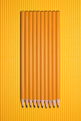 top view of arranged graphite pencils placed in row on yellow
