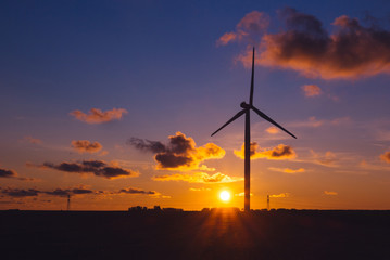 Obraz premium Wind turbines for electrical power generation in Normandy, France. Countryside and industrial landscape at sunset. Renewable energy sources. Environment friendly energy production