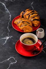 Coffee in a red cup with chocolate Croissant on the Dark Marble Background.Cappuccino or latte .Breakfast. Copy space for Text.