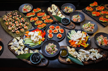 Traditional Asian snacks.Top view/Vegetables, bruschetta, cheese and other Asian snacks on a dark wooden table