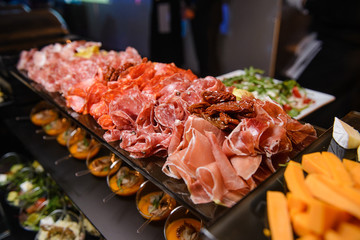 Various meat snacks on a dark parrot in a restaurant : chorizo, jamon, dried meat. Selective focus