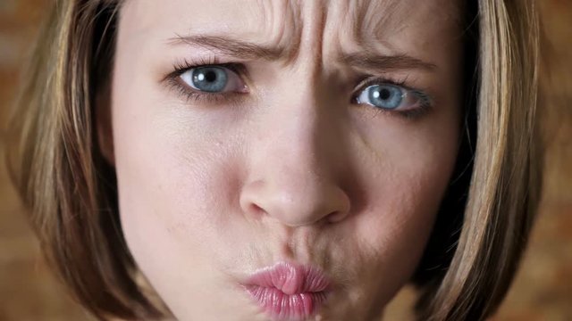 Young attractive girl is winking, duck face, fool around, watching at camera, brick background