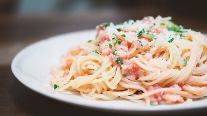 Close-up image of spaghetti sauce tarako which made from fresh cod fish in Japan and mixed with Thai coriander on the top of white plate and famous italian-japanese menu dish in Thailand restaurant