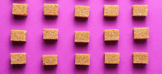 Food background with brown sugar on purple color paper.
